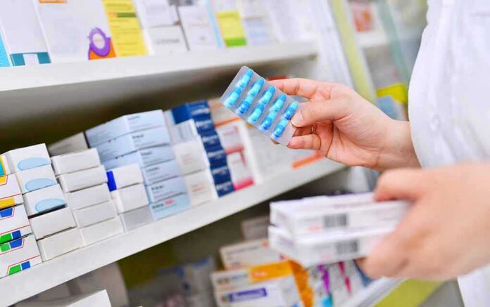 pharmacist holding blister pack of blue capsules